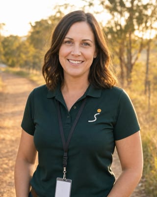 Followurpath support worker in a branded polo, smiling on a countryside path at golden hour